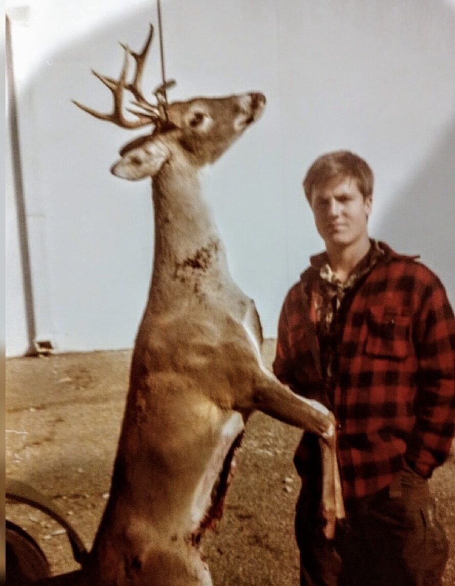 A young Jeb Bradshaw in a red plaid jacket standing beside his first buck, hanging outside Cogdell's Westview in Waco.