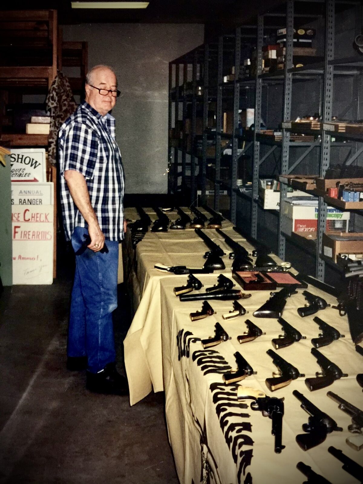 Leo Bradshaw standing in a room displaying collectible handguns on long tables.