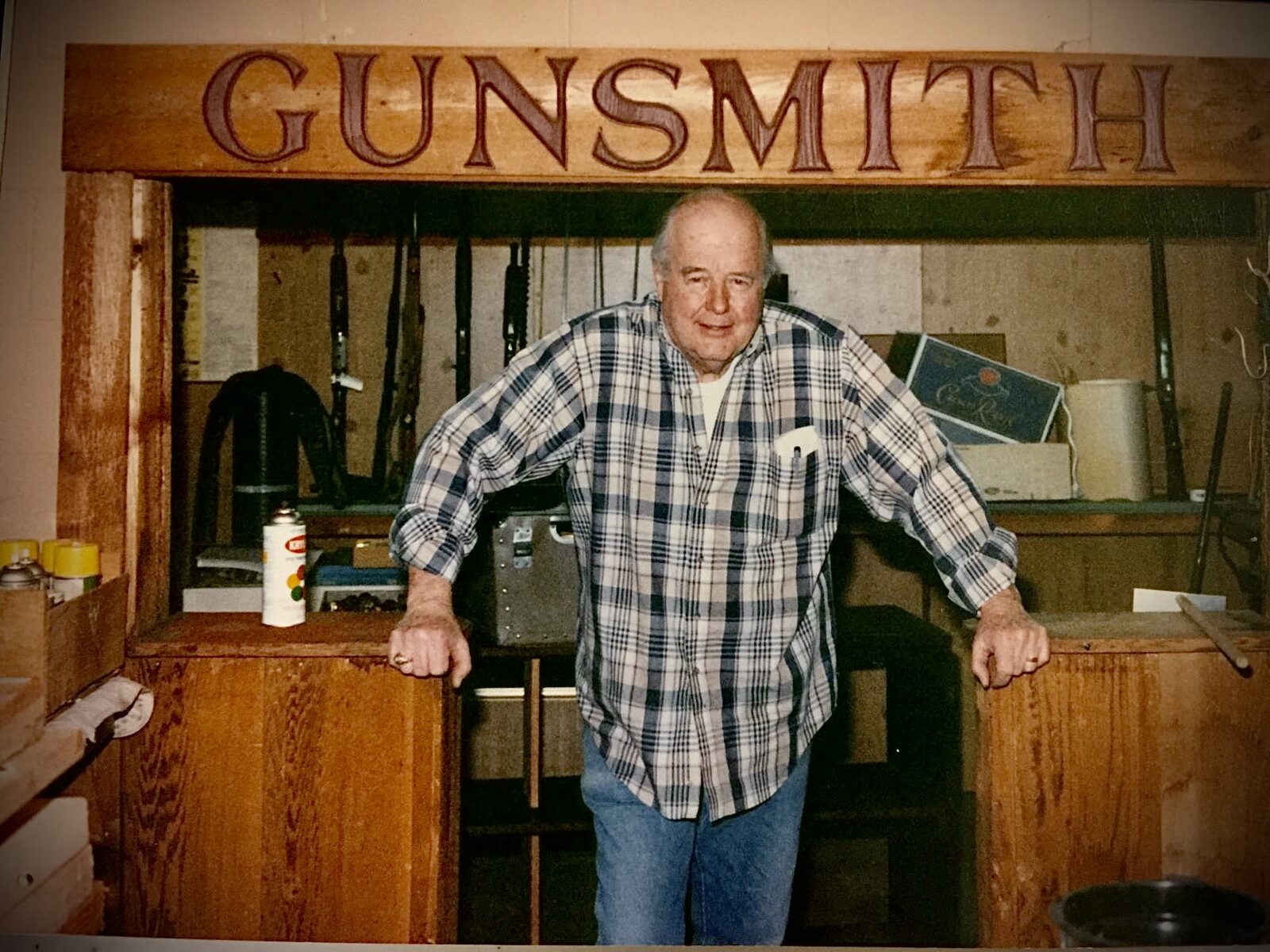 Leo Bradshaw leaning at the counter of the gunsmith room inside the shop.